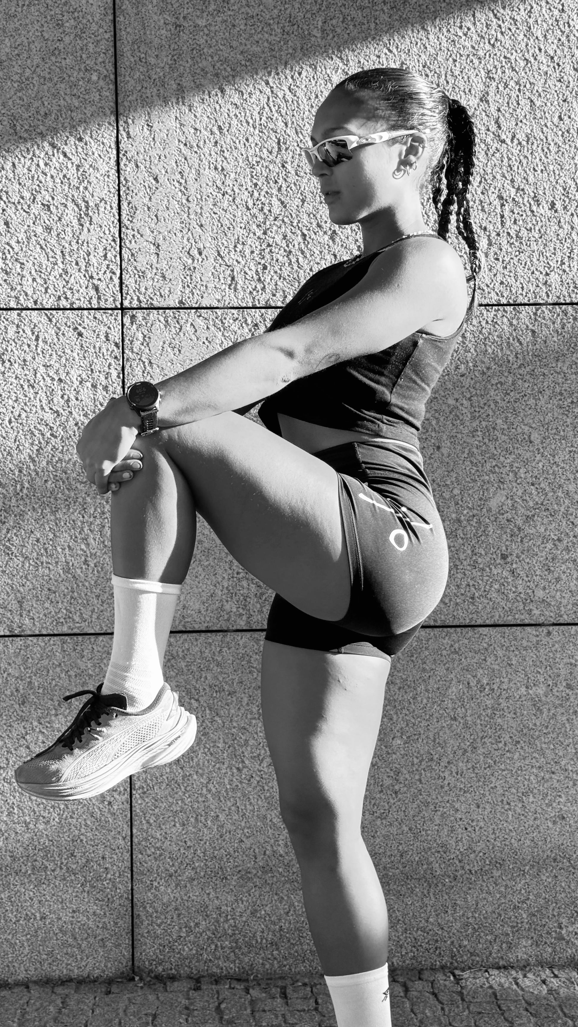 Woman athlete wearing Women’s Training Shorts — knee lift, side profile, outdoor wall