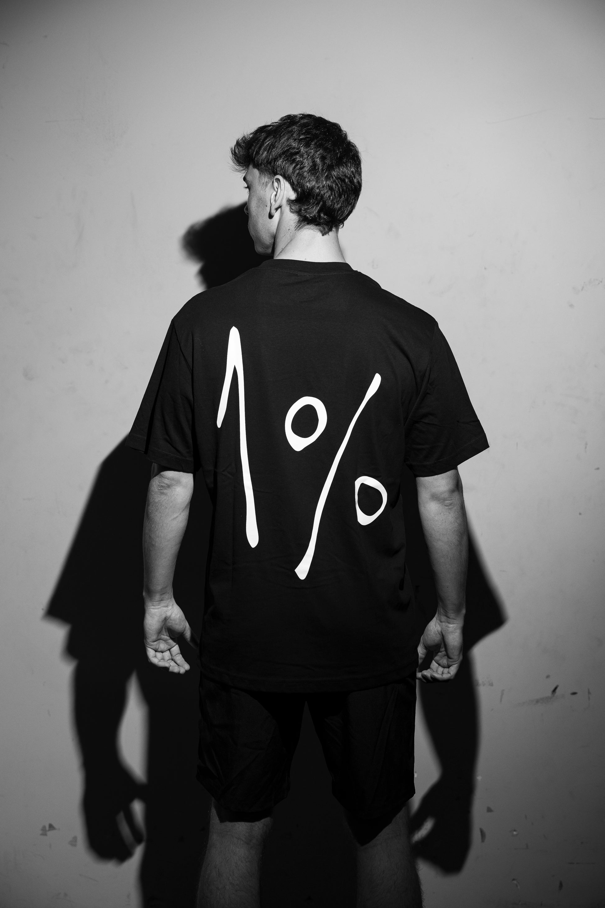 Model wearing oversized black T-shirt — back view with large 1% print